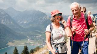 Gruppe von Senioren wandert in der Sonne am Berg