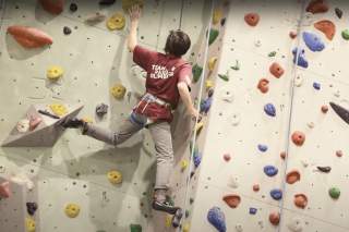 Jugendlicher Paraclimber klettert eine schwere Route.