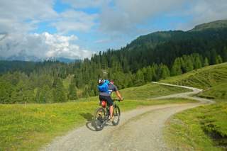 Mountainbiker auf einem Wirtschaftsweg über flache Berghänge.